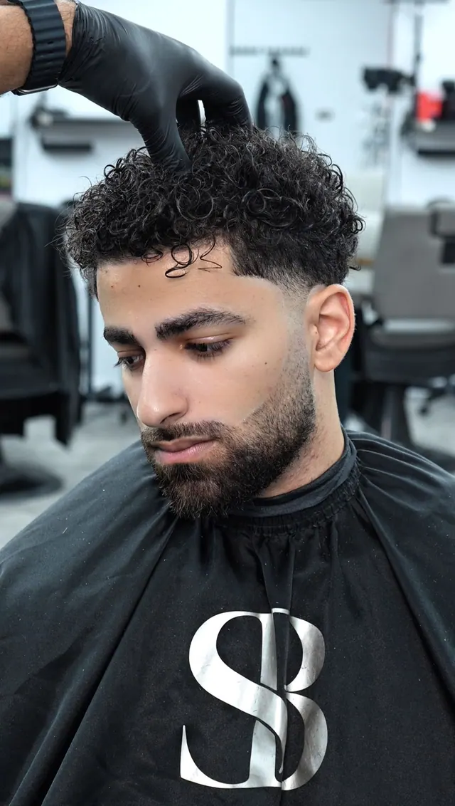 Curly top with a taper and a beard